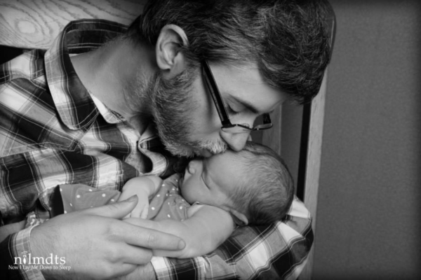 A man kissing a baby.  Learn More at Now I Lay Me Down to Sleep
